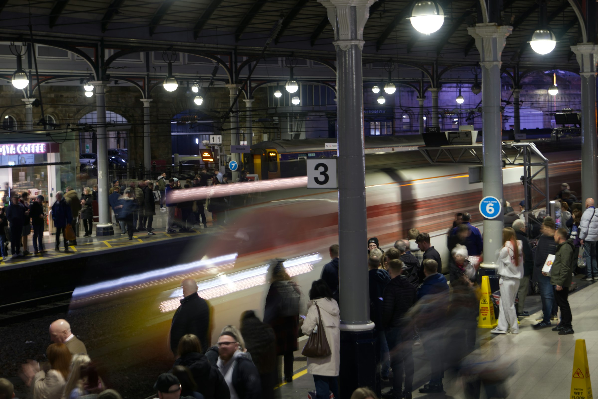 Football supporters waiting as a train arrives at Newcastle station at night